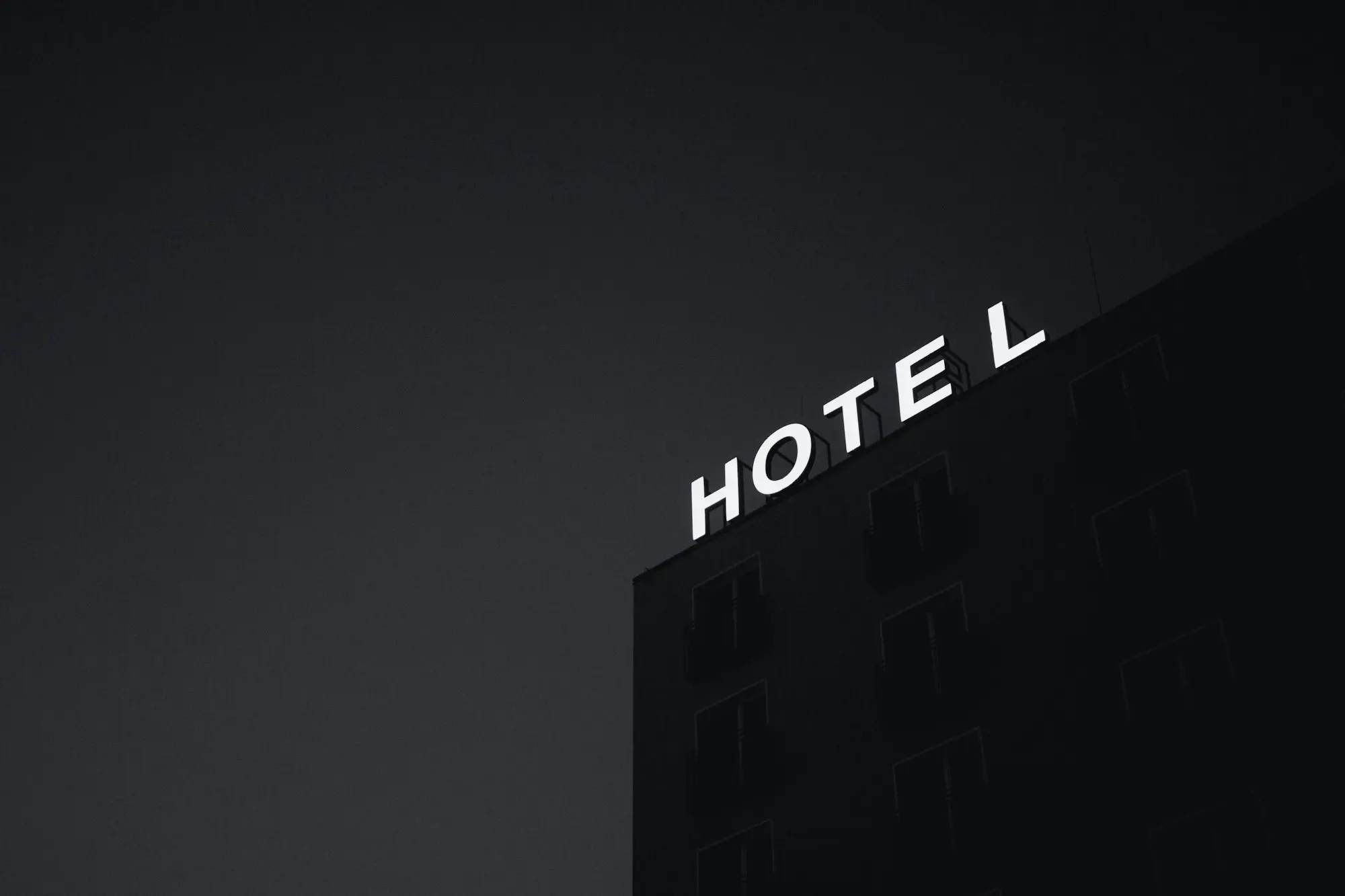 Neon sign reading “Hotel” on a façade at night